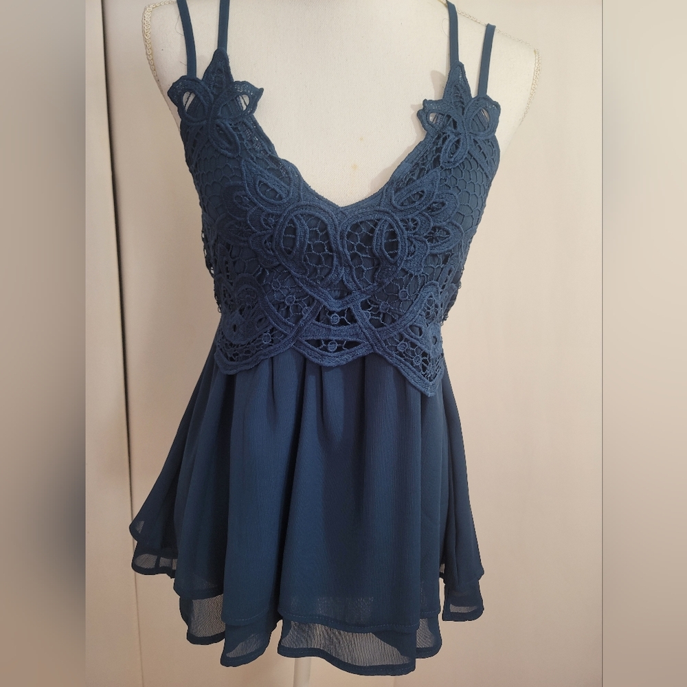 ,Feager blue top with crocheted flowers on top .